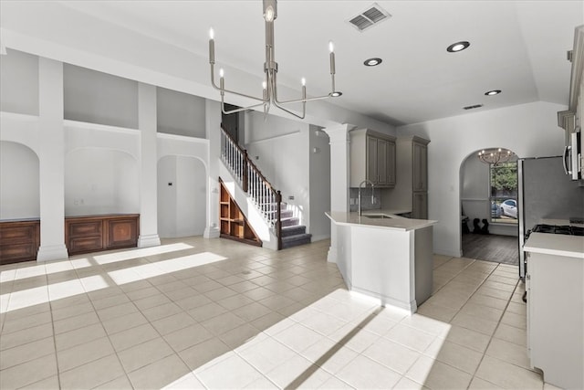 kitchen with gray cabinetry, sink, light tile patterned floors, and stainless steel fridge