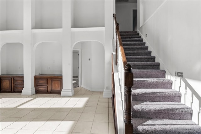 stairs featuring a towering ceiling and tile patterned floors