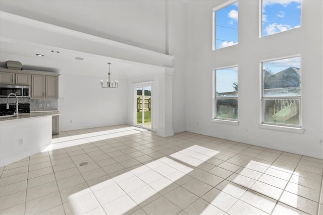 unfurnished living room featuring a high ceiling, light tile patterned floors, and a notable chandelier