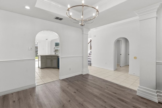 empty room with light hardwood / wood-style flooring, crown molding, and a tray ceiling