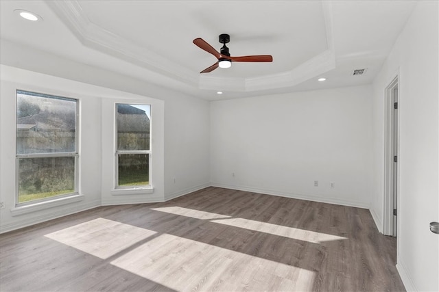 empty room with hardwood / wood-style floors, ceiling fan, crown molding, and a tray ceiling