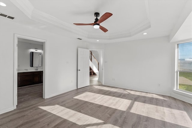 spare room featuring ornamental molding, a tray ceiling, ceiling fan, and light hardwood / wood-style flooring