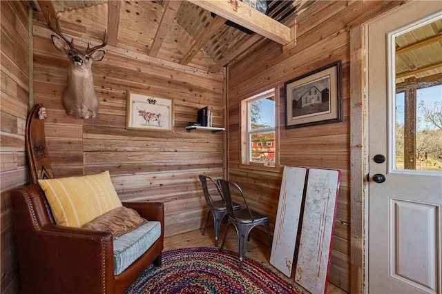 living area with beamed ceiling, wooden ceiling, and wood walls