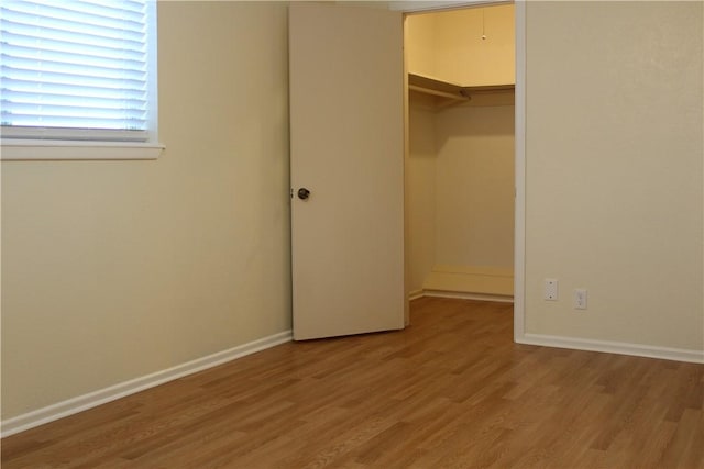 unfurnished bedroom with a spacious closet, hardwood / wood-style floors, and a closet