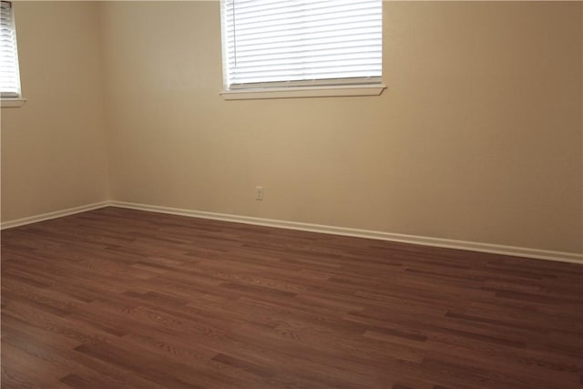 spare room with dark wood-type flooring and a healthy amount of sunlight