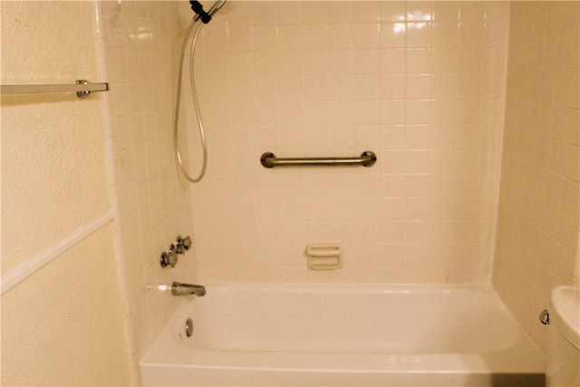 bathroom featuring toilet and tiled shower / bath