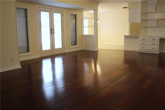 empty room featuring dark wood-type flooring, french doors, and ornate columns