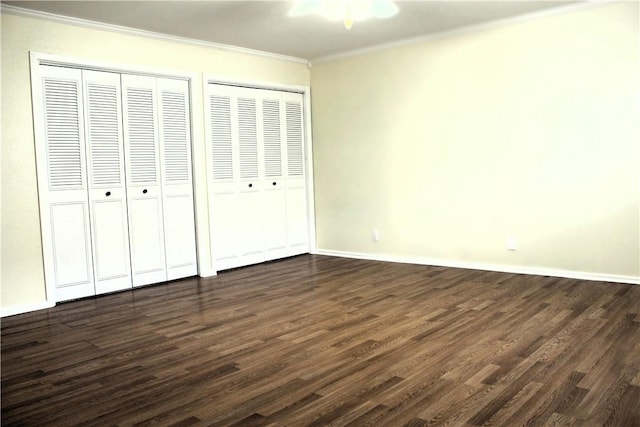 unfurnished bedroom with multiple closets, dark hardwood / wood-style floors, and crown molding