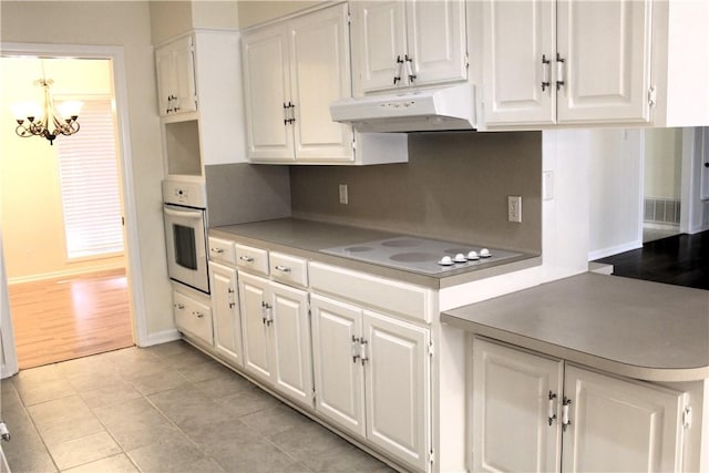 kitchen featuring white appliances, a notable chandelier, decorative backsplash, and white cabinets