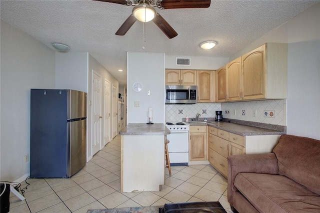 3938 Surfside Blvd Unit 2201, Corpus Christi, TX 78402 - kitchen with stainless steel appliances, light brown cabinets, open floor plan, backsplash, and a textured ceiling