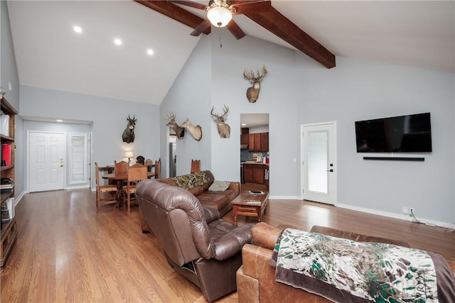 living room featuring beamed ceiling, ceiling fan, light wood-type flooring, and high vaulted ceiling