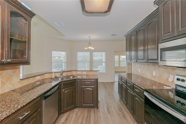 kitchen with dark brown cabinets, light wood-type flooring, stainless steel appliances, and sink