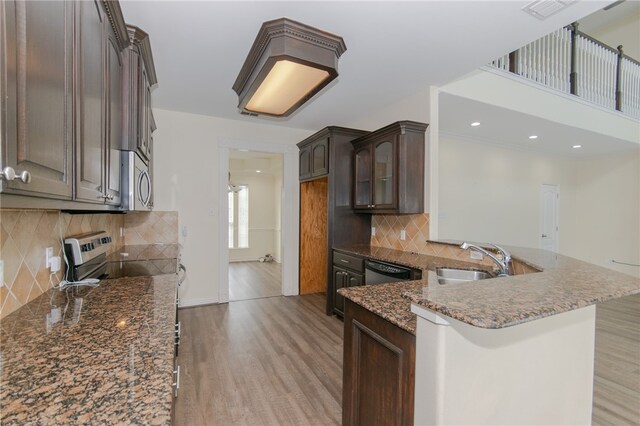 kitchen with dark brown cabinetry, sink, stainless steel appliances, decorative backsplash, and light wood-type flooring