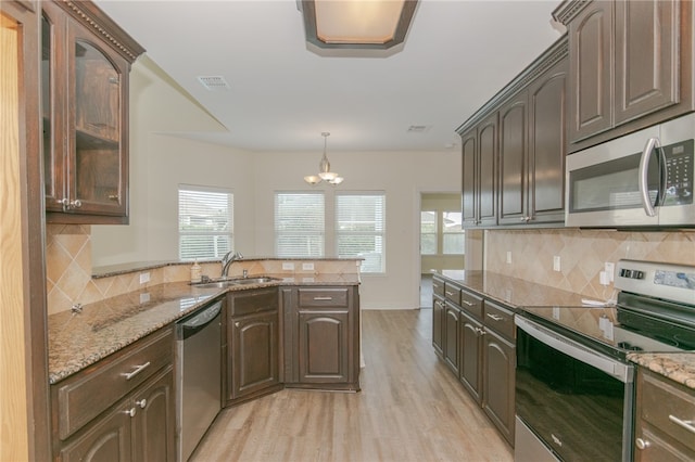 kitchen with light wood-type flooring, light stone counters, dark brown cabinets, stainless steel appliances, and sink