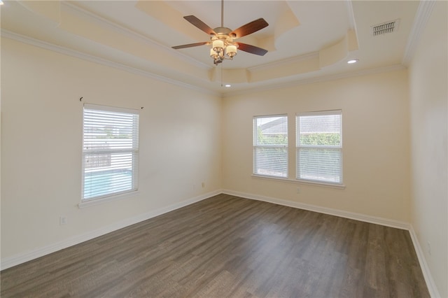 spare room with a tray ceiling, crown molding, dark hardwood / wood-style floors, and a healthy amount of sunlight