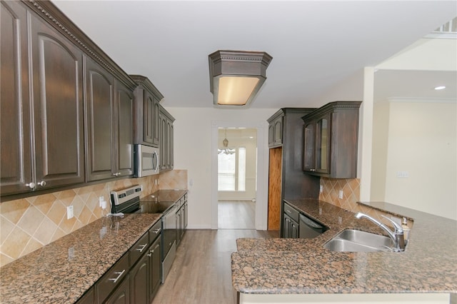 kitchen with appliances with stainless steel finishes, dark brown cabinetry, light hardwood / wood-style floors, and sink