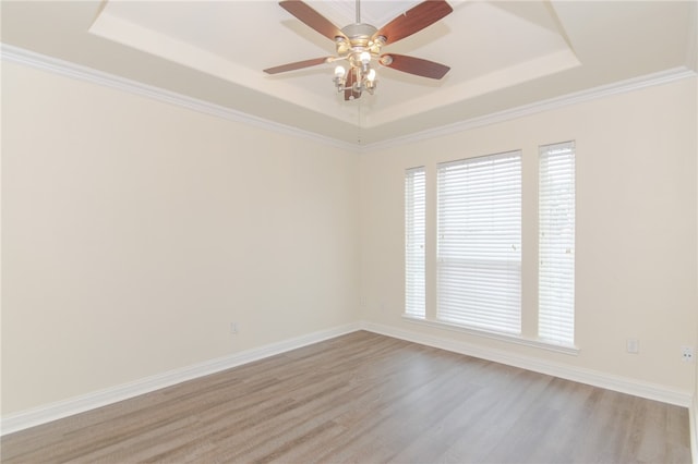 unfurnished room with light hardwood / wood-style floors, a raised ceiling, and ornamental molding