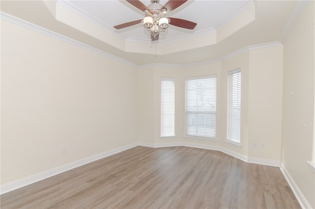 empty room featuring a tray ceiling, crown molding, light hardwood / wood-style flooring, and ceiling fan