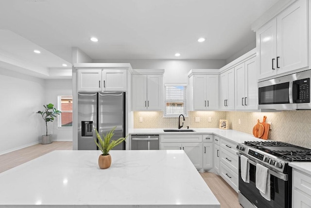 kitchen with white cabinetry, appliances with stainless steel finishes, decorative backsplash, and a sink