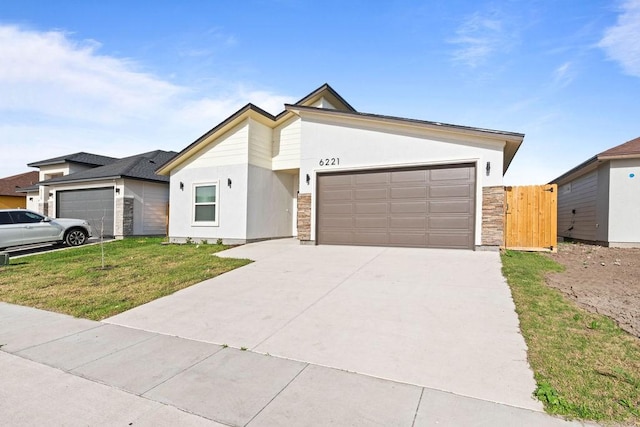 mid-century home with stucco siding, a front yard, a garage, stone siding, and driveway