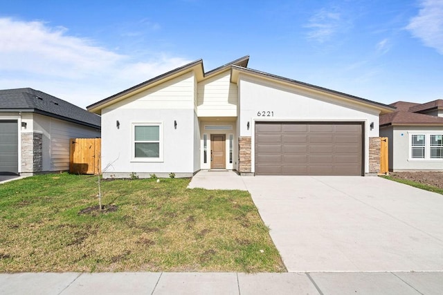 mid-century home featuring concrete driveway, an attached garage, fence, a front lawn, and stucco siding