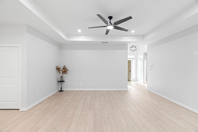 spare room with baseboards, a tray ceiling, recessed lighting, and light wood-style floors