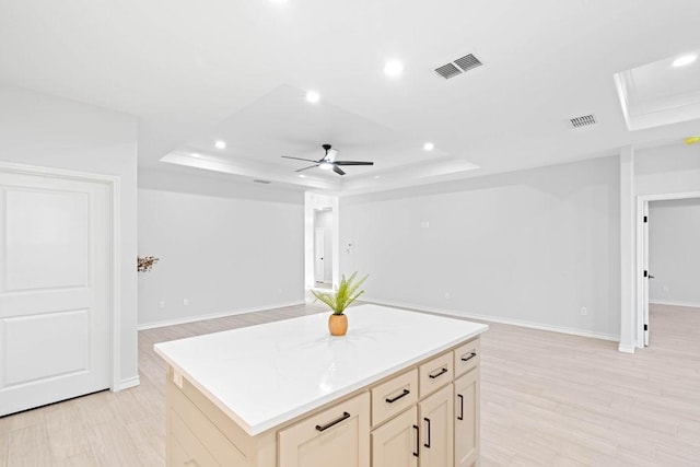 kitchen featuring visible vents, a kitchen island, a tray ceiling, and open floor plan