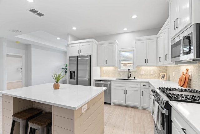 kitchen with tasteful backsplash, visible vents, appliances with stainless steel finishes, a sink, and a kitchen island