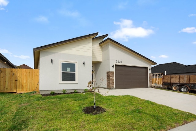 mid-century inspired home with a garage, driveway, a front yard, and fence