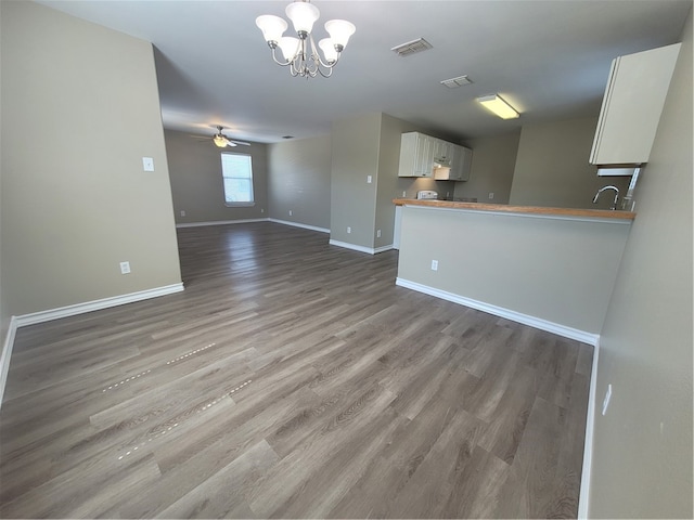 unfurnished living room with hardwood / wood-style flooring, ceiling fan with notable chandelier, and sink