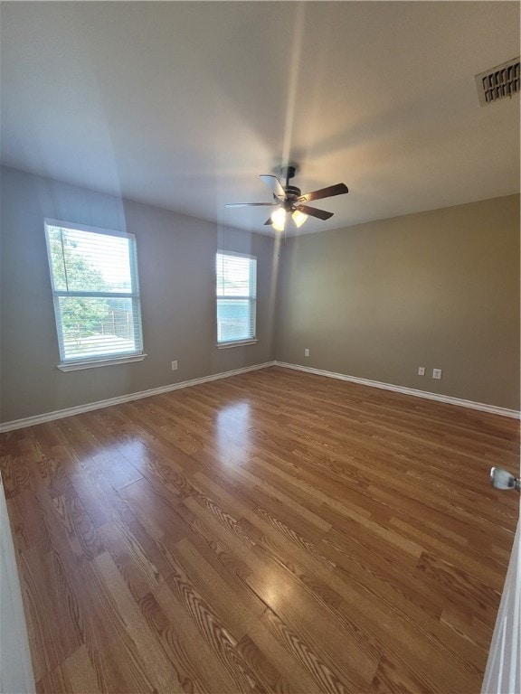 spare room with hardwood / wood-style flooring, ceiling fan, and a healthy amount of sunlight