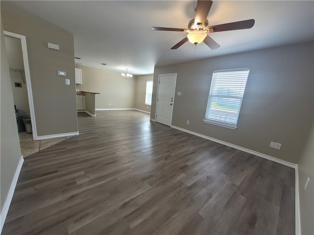 unfurnished living room with dark hardwood / wood-style floors and ceiling fan with notable chandelier