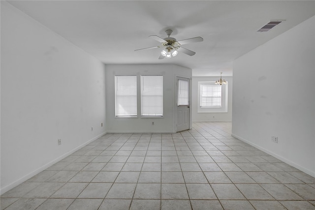 spare room featuring light tile patterned floors and ceiling fan with notable chandelier