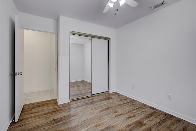 unfurnished bedroom featuring ceiling fan, a closet, and light wood-type flooring