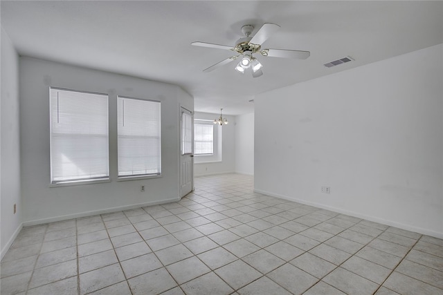 tiled empty room with ceiling fan with notable chandelier