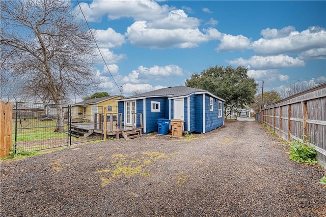 back of property featuring gravel driveway, fence, and a deck