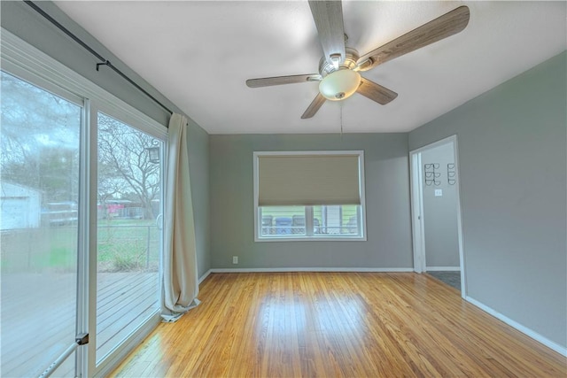 empty room with a ceiling fan, light wood-type flooring, plenty of natural light, and baseboards