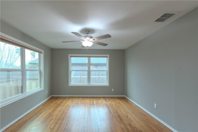 unfurnished room with a ceiling fan, light wood-style flooring, visible vents, and baseboards