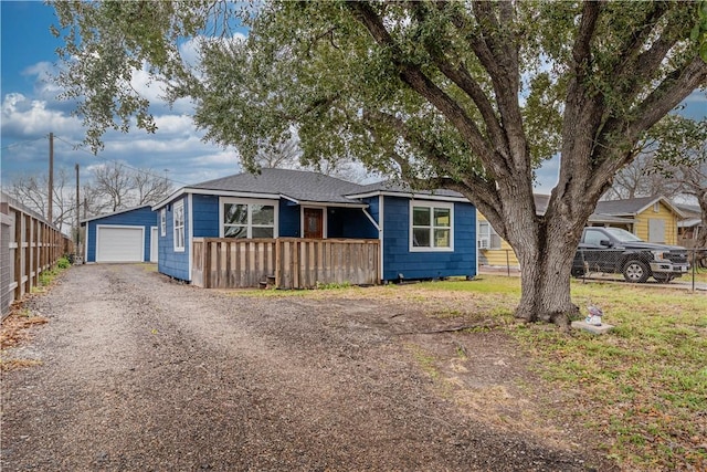 view of front of property with driveway, a detached garage, and fence