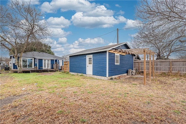 back of property featuring fence, a lawn, and an outdoor structure