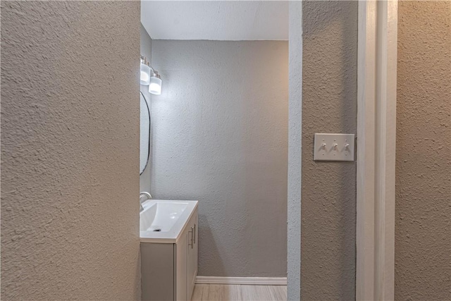 bathroom with a textured wall, wood finished floors, and vanity