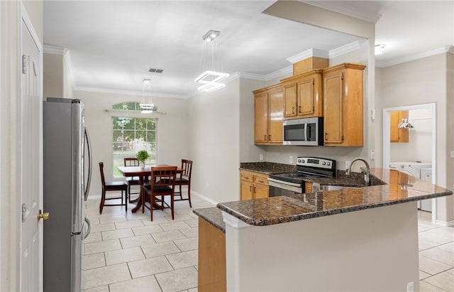 3613 Berkeley Dr, Corpus Christi, TX 78414 - kitchen featuring stainless steel appliances, light tile patterned floors, a peninsula, dark stone counters, and washer / clothes dryer