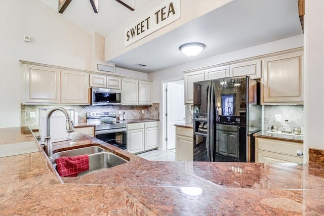 kitchen with stainless steel appliances, a sink, decorative backsplash, and cream cabinets