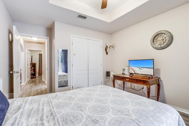 bedroom with wood finished floors, a closet, ceiling fan, and baseboards