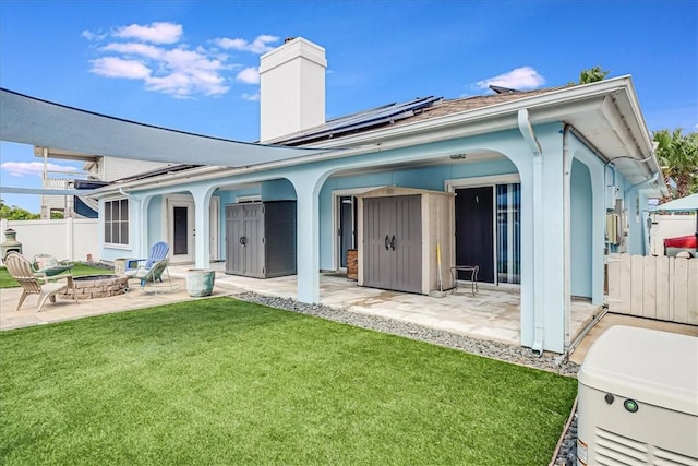 rear view of property with an outdoor fire pit, roof mounted solar panels, a patio, and a chimney
