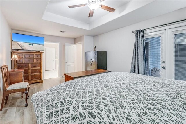 bedroom featuring light wood-style floors, a tray ceiling, and ceiling fan