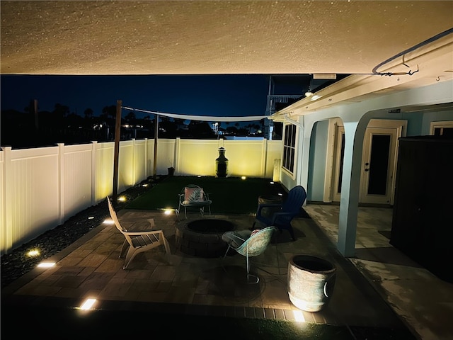 patio at twilight with a fire pit and a fenced backyard
