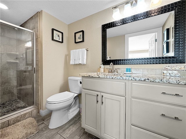 bathroom featuring walk in shower, hardwood / wood-style floors, a textured ceiling, toilet, and vanity