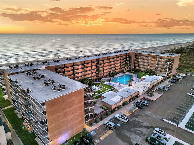 aerial view at dusk with a beach view and a water view