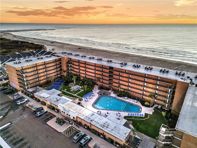 aerial view at dusk with a water view and a beach view